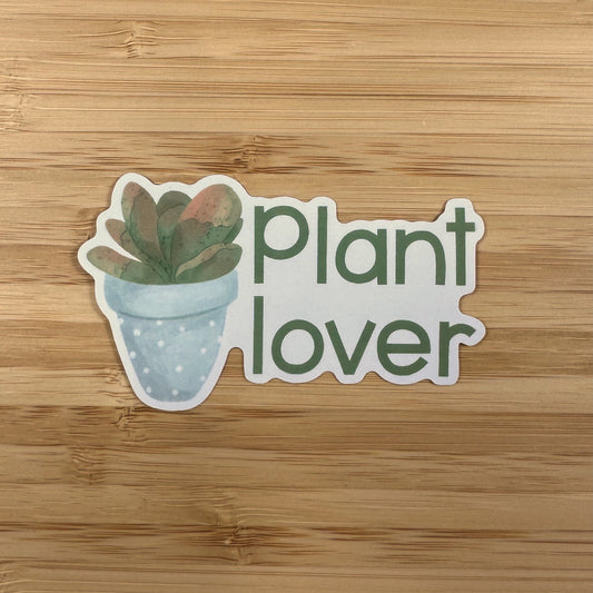 a plant lover sticker sitting on top of a wooden table