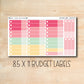a pink and yellow planner sticker on a wooden surface