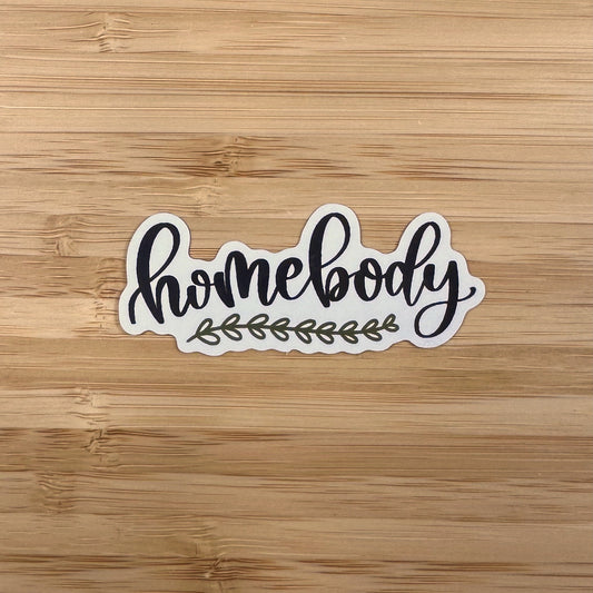 a sticker that says home body on a wooden surface