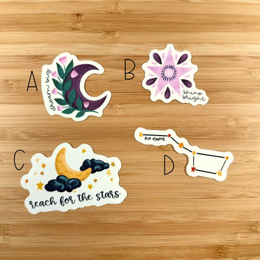 four stickers of different shapes and sizes on a wooden surface